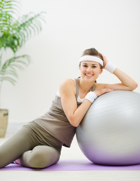 Happy woman sitting near fitness ball - Фото, изображение