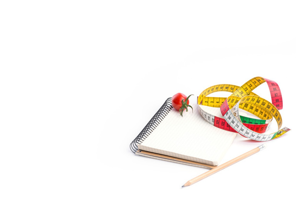 Notebook met meting van tape, potlood en tomaten op wit - Foto, afbeelding