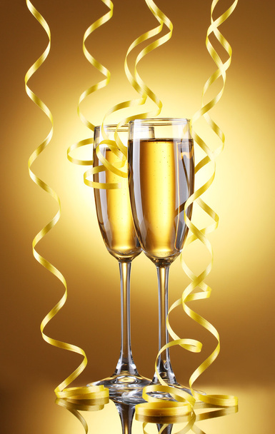 Glasses of champagne and streamer on yellow background - Photo, Image