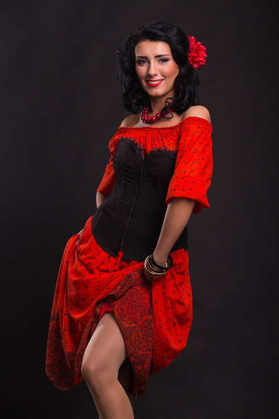 Beautiful woman in a red dress dancing on a black background - Foto, afbeelding