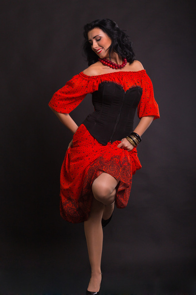 Belle femme dans une robe rouge dansant sur un fond noir
 - Photo, image