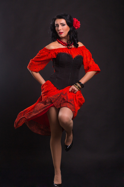 Beautiful woman in a red dress dancing on a black background - Photo, Image