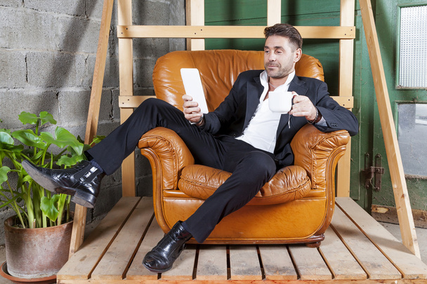 young businessman sitting in his chair watching smart phone - Foto, Imagen