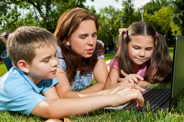 Happy Family käyttää kannettavaa tietokonetta nurmikolla
 - Valokuva, kuva