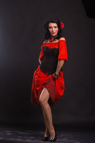 schöne Frau in rotem Kleid tanzt auf schwarzem Hintergrund - Foto, Bild