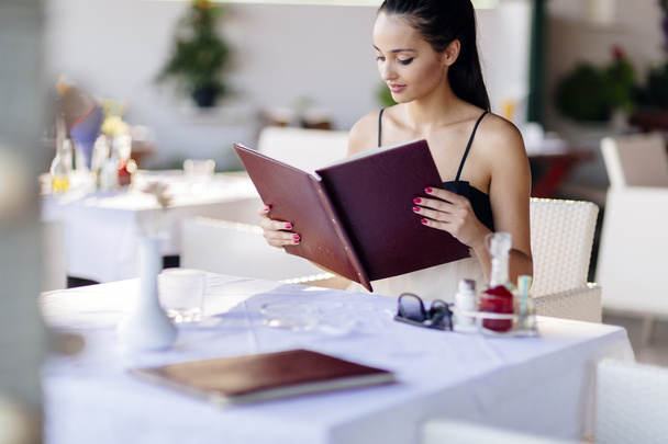 Beautiful woman ordering from menu - Фото, изображение
