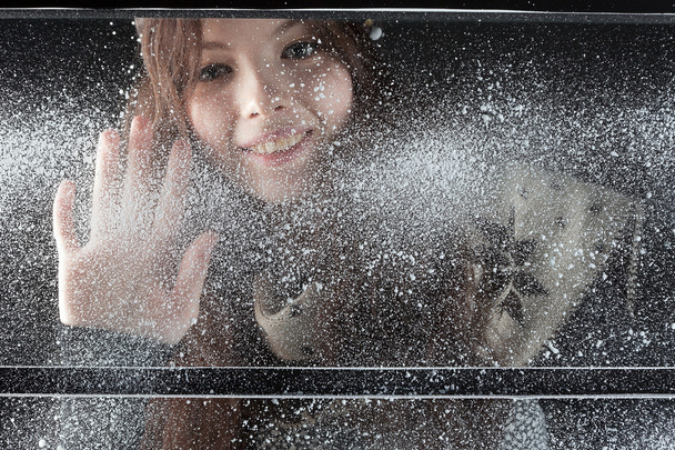 Young happy girl behind snow window - Φωτογραφία, εικόνα