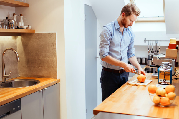 Homem cortando laranjas na cozinha
 - Foto, Imagem