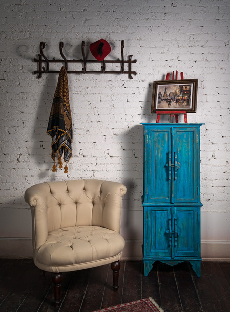 Πολυθρόνα vintage μπεζ, μπλε ντουλάπι, κρεμάστρα τοίχου, κασκόλ και ζωγραφική - Φωτογραφία, εικόνα