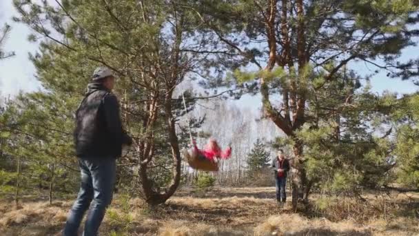 Gomel, Belarus - April 3, 2016: Family in a forest glade ride on a swing. - Footage, Video