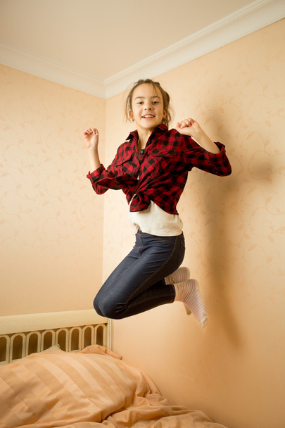 Happy teenage girl in shirt jumping on bed  - Valokuva, kuva