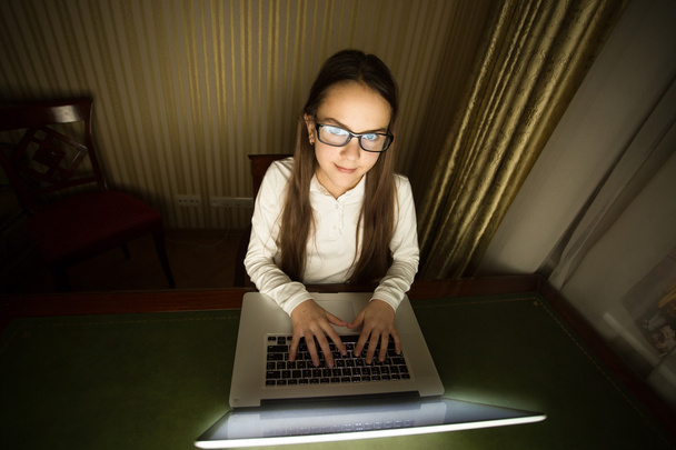 Teenage girl sitting in dark room with laptop - Photo, Image