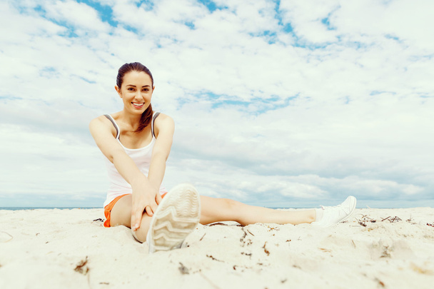 Young woman training on beach outside - Фото, изображение