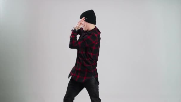 Hip-hop tanec v čepici tance ve fotoateliéru s šedým pozadím - Záběry, video