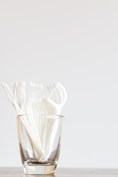 Προφορική συσκευή: οδοντικό νήμα σε ποτήρι σε φόντο ξύλινη - Φωτογραφία, εικόνα