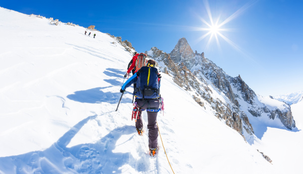 Ορειβατών ανεβείτε ένα χιονισμένο κορυφή. Στο παρασκήνιο, η διάσημη κορυφή D - Φωτογραφία, εικόνα