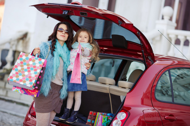 A woman with a child after shopping load the car - Foto, Imagen