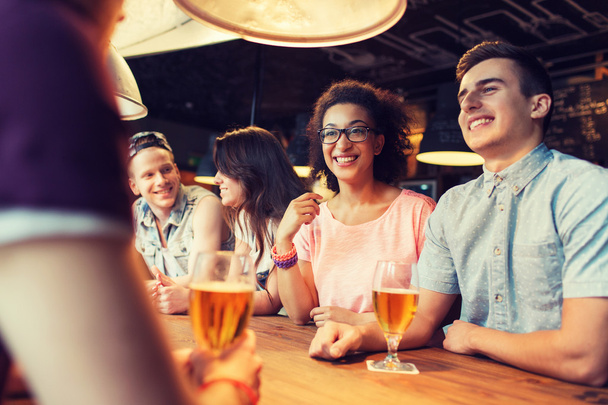 happy friends drinking beer and talking at bar - Zdjęcie, obraz