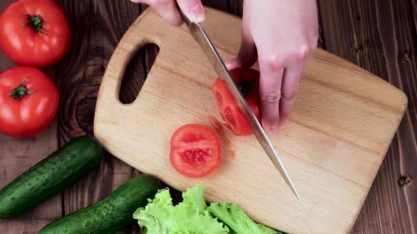 Cook Cuts Tomato on the Board. on the Table Are Cucumbers and Salad Leaves. Top View. - Metraje, vídeo