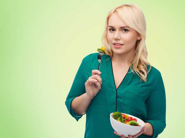 улыбающаяся молодая женщина ест овощной салат
 - Фото, изображение