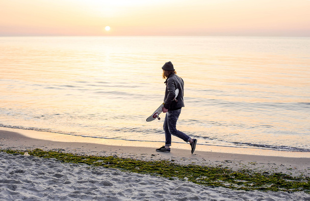 man with skate on beach during sunset on sunrise - Zdjęcie, obraz