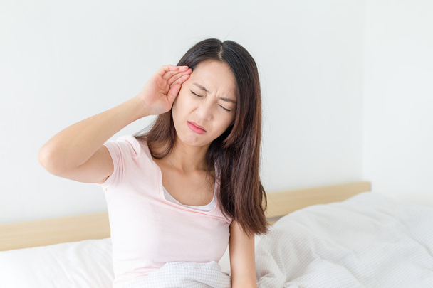 Kadın duygu baş ağrısı ve yatak üzerinde oturan - Fotoğraf, Görsel