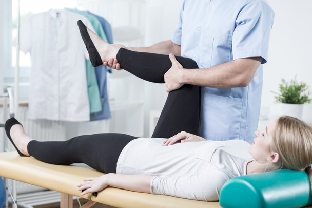 Chiropractor stretching female leg - 写真・画像