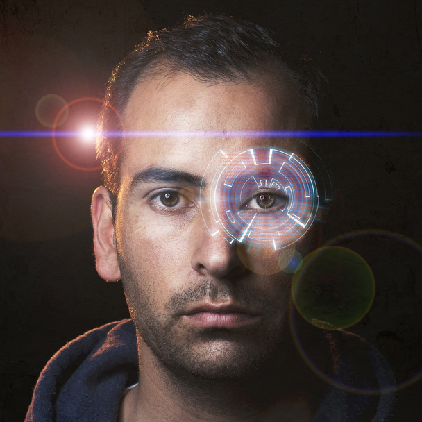 Φουτουριστικό πορτρέτο ενός νεαρού άνδρα με ολόγραμμα στο ένα μάτι και ταινία όπως φακού φωτοβολίδα - Φωτογραφία, εικόνα
