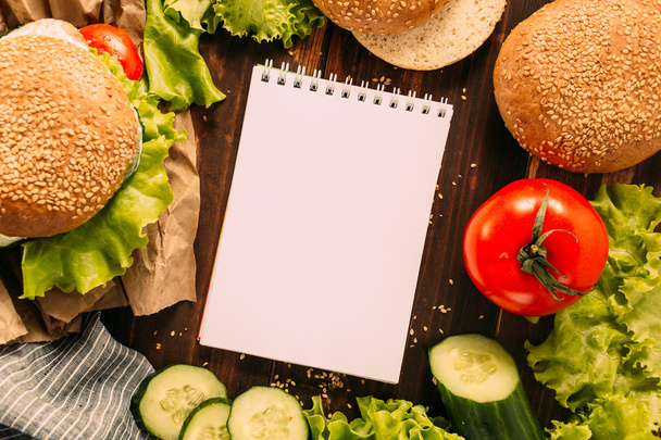 Burger z składników i notatnik na stole - Zdjęcie, obraz