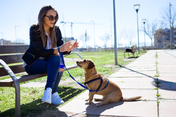 Beautiful young woman with her dog using mobile phone. - Foto, Imagem