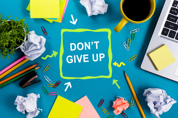 Dont give up. Office table desk with supplies, white blank note pad, cup, pen, pc, crumpled paper, flower on blue background. Top view - Fotoğraf, Görsel