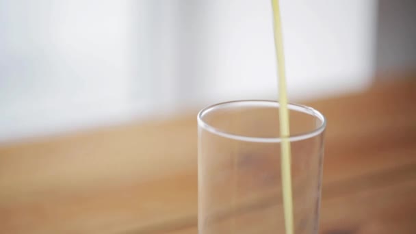 orange juice pouring into glass on wooden table - Video
