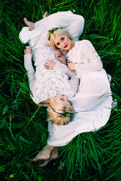 twins sisters lying on green grass - Фото, изображение