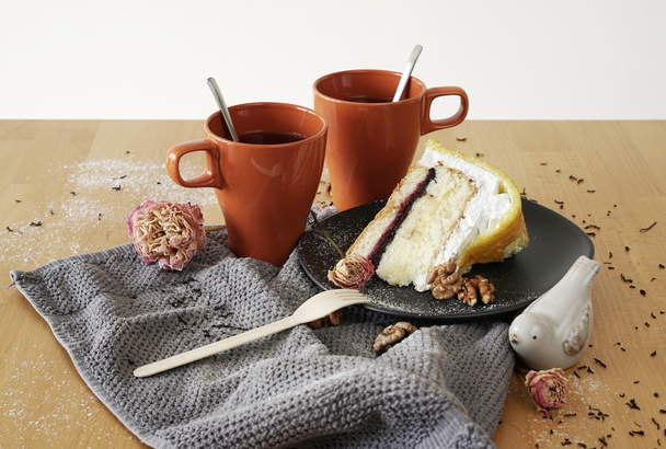 zwei Teetassen auf dem Tisch mit dem Kuchen. die Zusammensetzung von Teetassen Kuchen, Tee, Blumen und Nüssen - Foto, Bild
