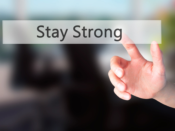 Stay Strong - Hand indrukken van een knop op de onscherpe achtergrond  - Foto, afbeelding