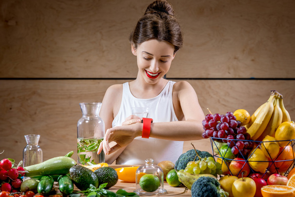 Молодая женщина использует умные часы на кухне
 - Фото, изображение
