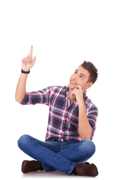 Seated young casual man pointing at something up - Photo, Image