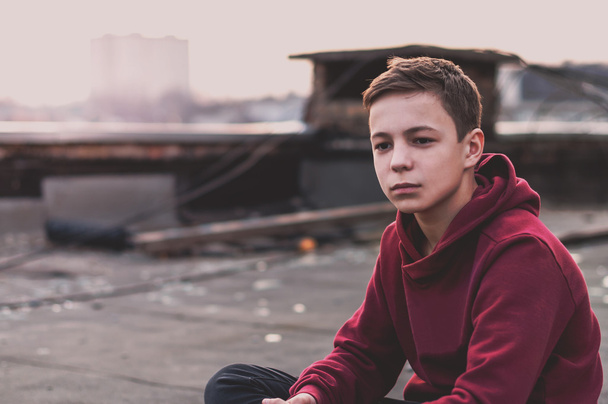 Zamyślony nastolatek siedzi na dachu domu - Zdjęcie, obraz