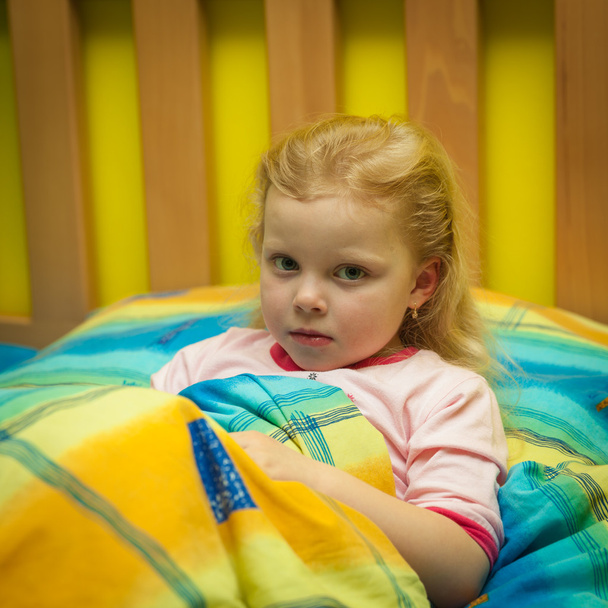 寝る木製ベッドの上のシーツに小さな女の子 - 写真・画像