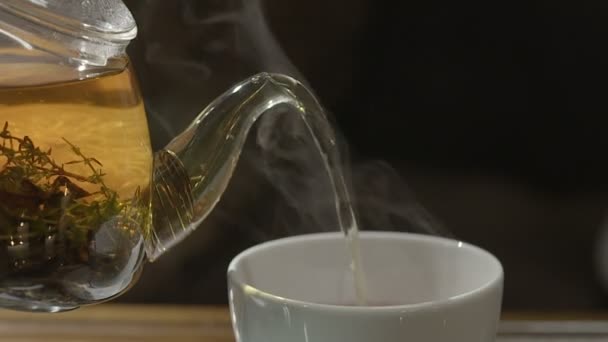 From transparent glass teapot pour black tea in two cups - Кадри, відео