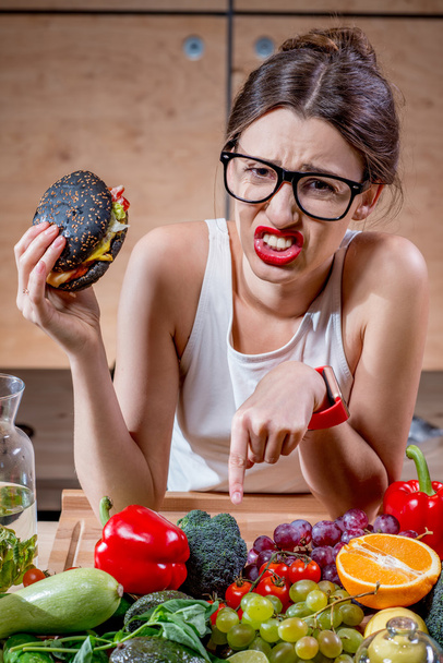 Woman choosing between fast food and healthy vegetables, fruits - Fotografie, Obrázek