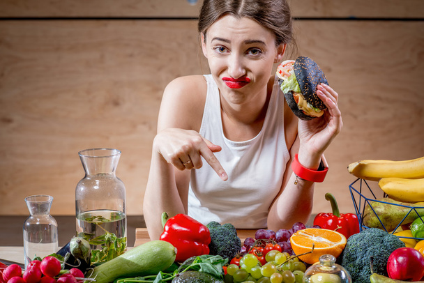 Woman choosing between fast food and healthy vegetables, fruits - Photo, Image