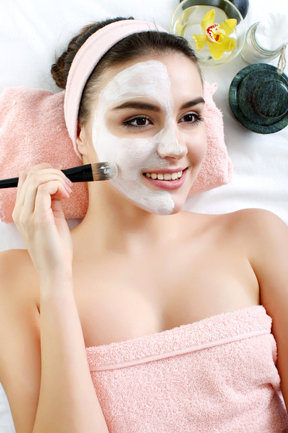 Woman with clay facial mask in beauty spa. - Photo, Image