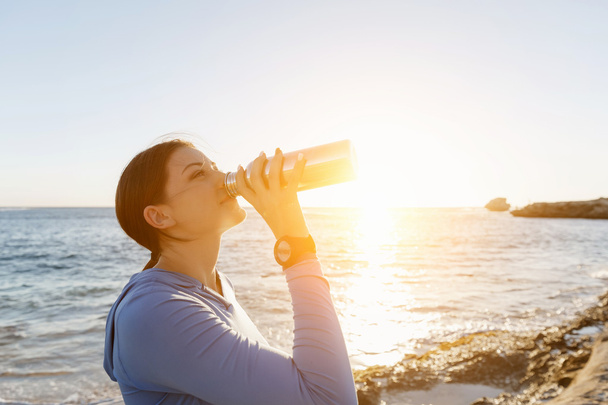 Woman drinking water on beach - Photo, Image