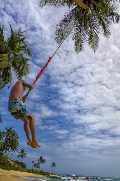 Person on the swings between palms - Φωτογραφία, εικόνα