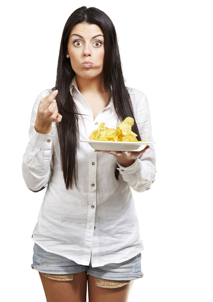 молодая женщина ест картофельные чипсы на белом фоне
 - Фото, изображение