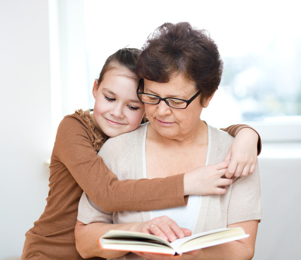 La abuela está leyendo el libro con su nieta
 - Foto, imagen