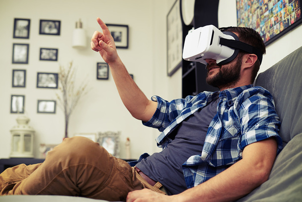 Mann drückt mit Virtual-Reality-Brille auf einen Knopf - Foto, Bild