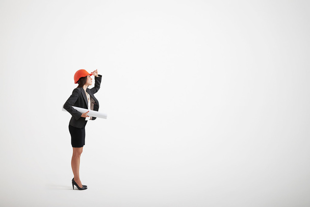 Mulher em desgaste formal e capacete de construção segurando plantas
 - Foto, Imagem