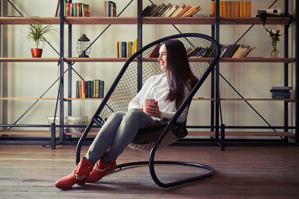 Nő ül egy designer szék, és keres el - Fotó, kép